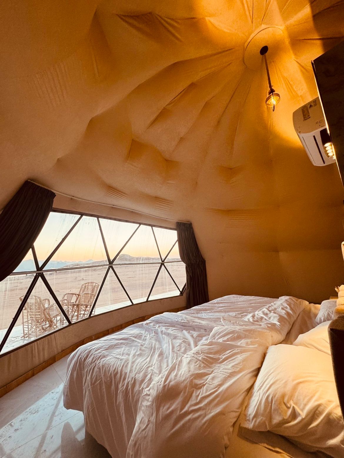 Interior of a traditional Bedouin-style bungalow with comfortable furnishings, modern amenities, and warm desert aesthetic lighting creating an inviting and peaceful atmosphere